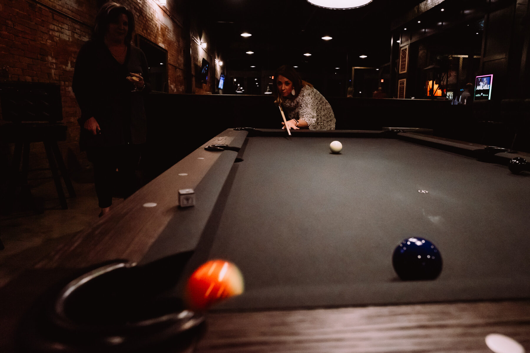 a eprson plays pool on a pool table at the Depot